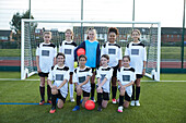 UK, Group portrait of girls soccer team (10-11, 12-13) in front of goal