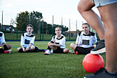 UK, Frauenfußballmannschaft (10-11, 12-13) sitzt während des Trainings auf dem Feld