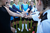 UK, Weibliche Fußballspielerinnen (10-11, 12-13) stapeln die Hände auf dem Feld
