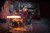 Forge workers pre form red hot billet into flight bar (mining component) on hammer