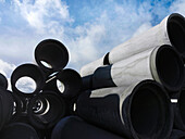 Concrete pipes piled against blue sky