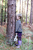 Junge (18-23 Monate) spielt Verstecken im Wald