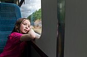 Mädchen (4-5) schaut durch ein Fenster im Zug