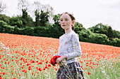 Girl (4-5) holding bunch of poppies in field