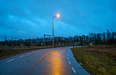 Country road with railroad crossing at dusk in rain