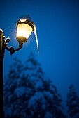 Snow covered illuminated lantern with icicle