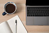 Laptop, Notizblock und Kaffee auf dem Schreibtisch