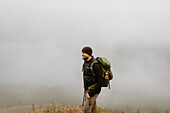 Kanada, Yukon, Whitehorse, Lächelnder Mann beim Wandern in einer nebligen Landschaft