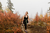 Canada, Yukon, Whitehorse, Woman hiking on footpath in foggy landscape