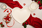 Heart-shaped plate and Valentines Day decorations on table