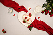 Herzförmiger Teller mit Baiser und Valentinstagsdekoration auf dem Tisch