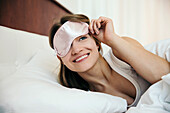 Junge Frau mit Augenmaske beim Aufwachen