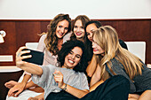 Fünf junge Frauen machen ein Selfie auf dem Bett