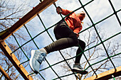 Low angle view of young woman on jungle gym