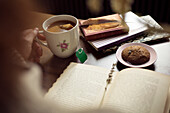 Frau hält Tee und Buch, Nahaufnahme der Hände