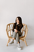 Studio shot of young woman sitting in wicker chair