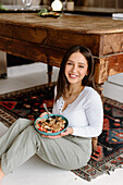 Smiling young woman holding granola bowl