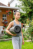 UK, London, Frau mit Yogamatte vor einem Haus stehend