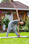 UK, London, Frau macht Yoga auf dem Rasen vor dem Haus