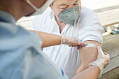 Österreich, Wien, Nahaufnahme einer Krankenschwester beim Anlegen eines Pflasters auf dem Arm eines Patienten