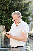 Austria, Vienna, Man with adhesive bandage on arm using smart phone outdoors