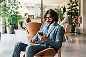 Italy, Businessman using laptop and smart phone in creative studio