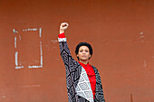 Italy, Tuscany, Pistoia, Woman standing against wall and raising fist
