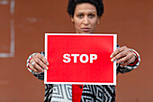 Italy, Tuscany, Pistoia, Woman holding stop sign