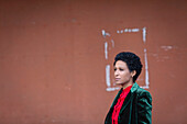 Italien, Toskana, Pistoia, Frau in metallischem Blazer steht an der Wand