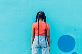 Italien, Mailand, Rückansicht einer Frau mit Zöpfen vor einer blauen Wand