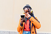 Italien, Mailand, Frau mit Kopfhörern und Smartphone im Freien