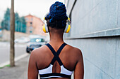 Italien, Mailand, Rückansicht einer Frau in Sportkleidung und Kopfhörern in der Stadt