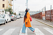 Italien, Mailand, Frau mit Gesichtsmaske beim Überqueren der Straße