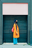 Italien, Mailand, Modische Frau mit Gesichtsmaske vor einem Gebäude