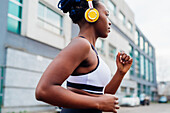 Italy, Milan, Woman with headphones jogging in city