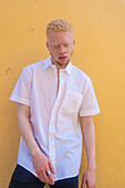 Deutschland, Köln, Albino-Mann in weißem Hemd vor gelber Wand