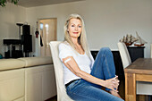 Austria, Vienna, Senior woman with adhesive bandage on arm sitting on chair