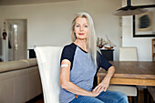 Austria, Vienna, Senior woman with adhesive bandage on arm sitting at table