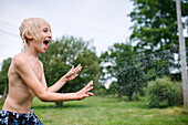 Canada, Ontario, Kingston, Shirtless boy (8-9) playing with water