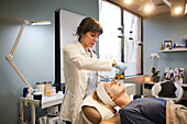 Beautician applying mask on patients face 