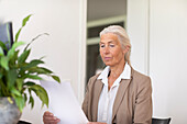 Mature businesswoman looking at document in office