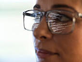 Close-up of computer programmer with data reflected in eyeglasses