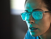 Close-up of programmer with binary code reflected in eyeglasses