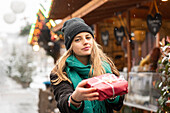 Young woman holding Christmas present outdoors