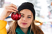 Portrait of young woman holding Christmas tree bauble