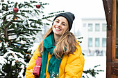 Portrait of smiling woman standing next to Christmas tree outdoors