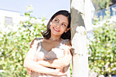 Smiling woman leaning against tree outdoors