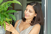 Smiling woman taking care of potted plant