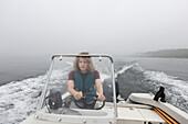 Junge (14-15) steuert Motorboot auf einem nebligen See