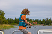 Junge (14-15) am See, mit Angelrute